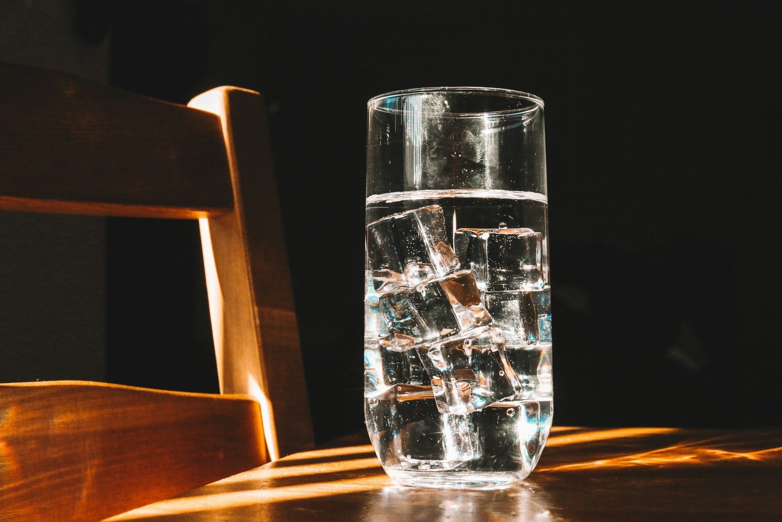 Eiswürfel in einem Glas auf einer Holzoberfläche